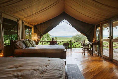 Safari tent interior at Katavi Wildlife Camp with bed and veranda overlooking the plains